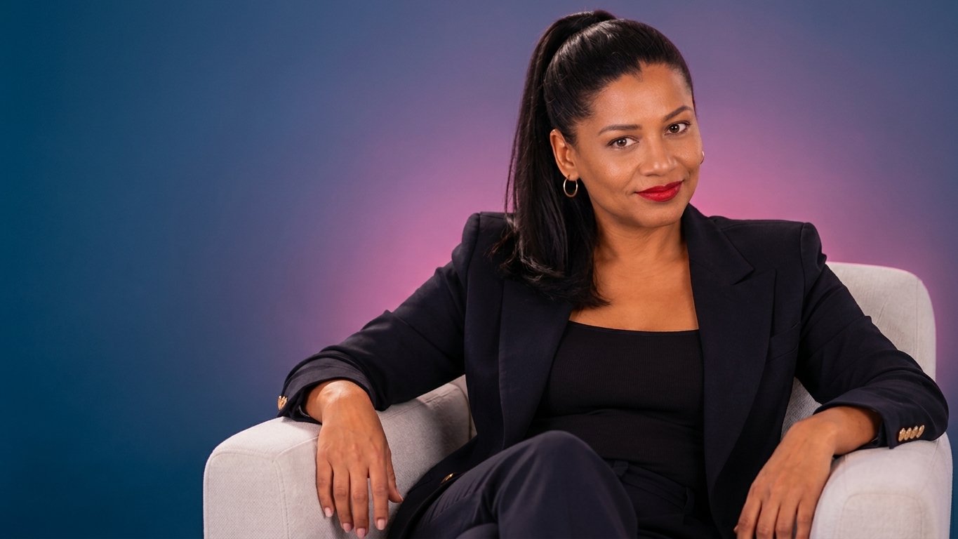 Gloria Cárdenas sentada en un sillón, sonriendo, con blazer oscuro